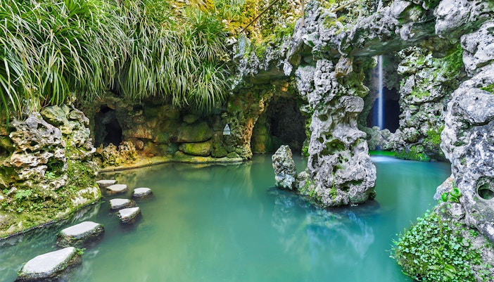 Sintra's Quinta da Regaleira garden with tourists exploring the ornate stone well.