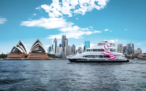 Sydney Harbour cruise ship near Opera House with city skyline.