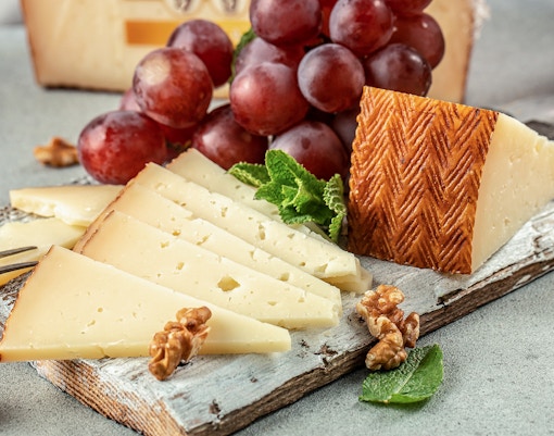 Spanish Manchego cheese tapas with olives and cured meats on a wooden board.
