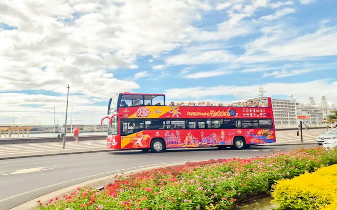 City Sightseeing bus near Rotunda do Infante Fountain, Funchal, with cruise ship in background.