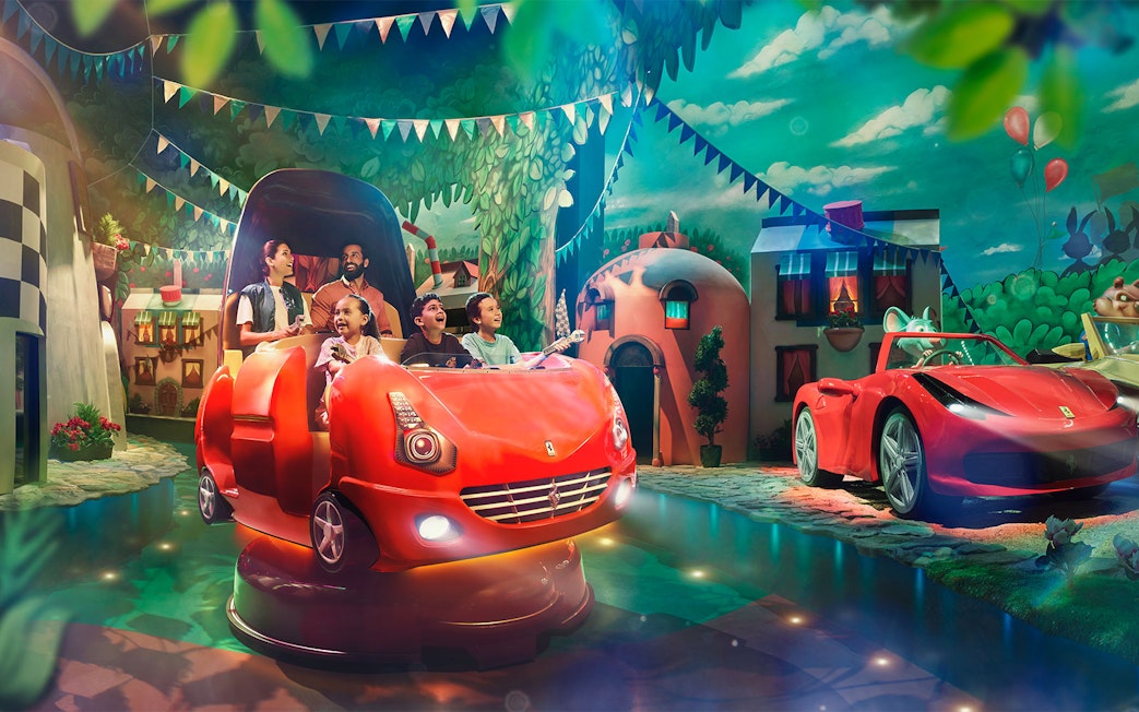 Visitors enjoying a ride at Ferrari World Abu Dhabi with vibrant decor and Ferrari-themed cars.