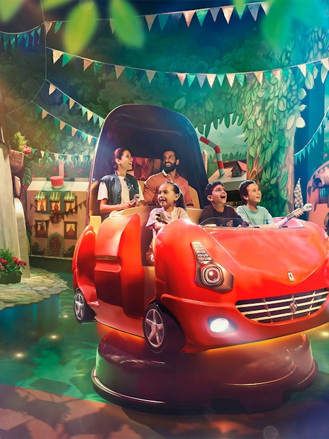Visitors enjoying a ride at Ferrari World Abu Dhabi with vibrant decor and Ferrari-themed cars.