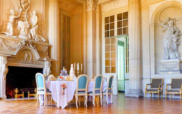 Elegant dining room with ornate fireplace and statues at Château de Maisons.
