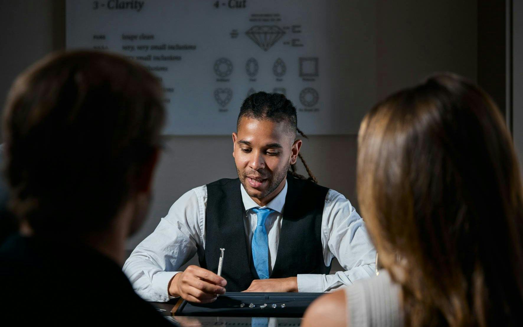 Jeweler explaining diamond selection to visitors at Royal Coster Diamonds.