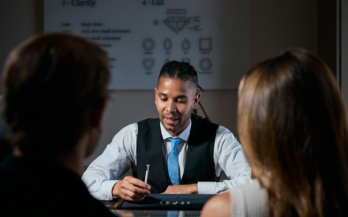 Jeweler explaining diamond selection to visitors at Royal Coster Diamonds.