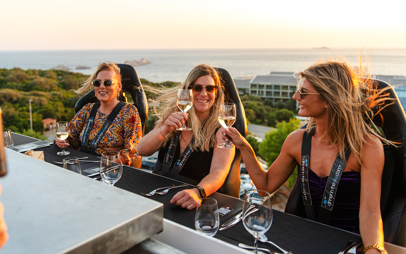 Guests toasting at Dinner in the Sky with a view of Dubrovnik coastline.