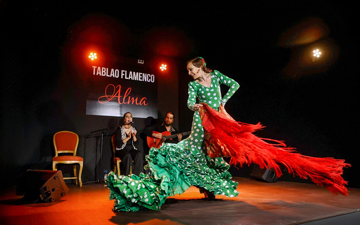 Flamenco dancer performing at Tablao Flamenco Alma with musicians in the background.