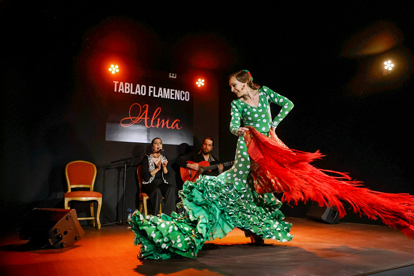 Flamenco dancer performing at Tablao Flamenco Alma with musicians in the background.