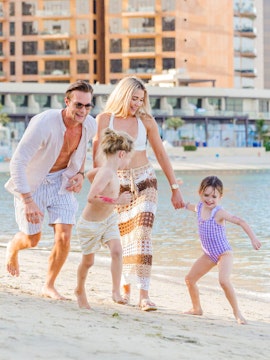 Family playing on the sandy shore at Riva Beach Club.