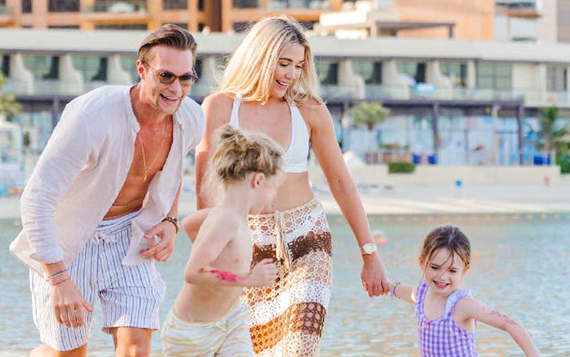 Family playing on the sandy shore at Riva Beach Club.