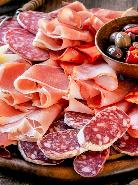 Charcuterie board with assorted meats, cheeses, and olives at a West End London restaurant.