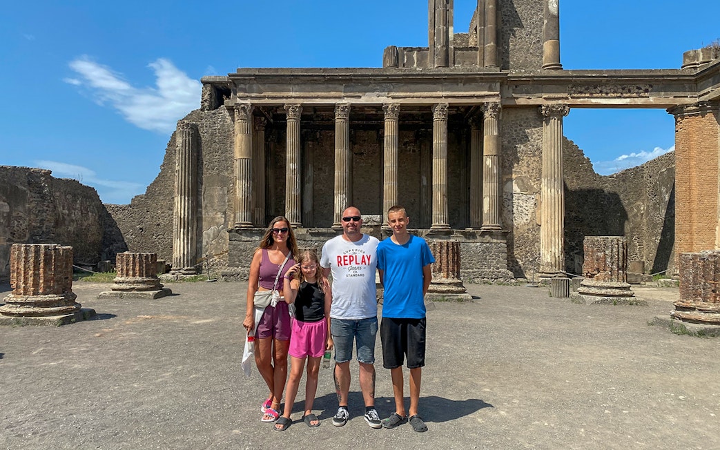 Family standing in front of ancient ruins in Pompeii, Italy.