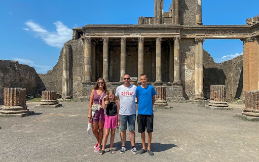 Family standing in front of ancient ruins in Pompeii, Italy.