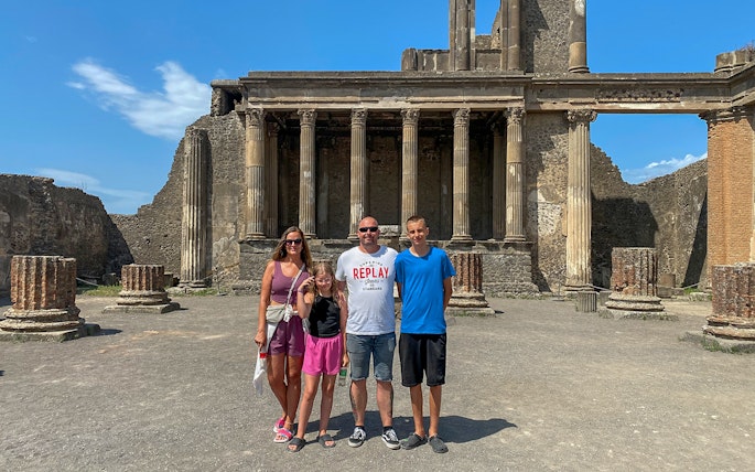 Family standing in front of ancient ruins in Pompeii, Italy.