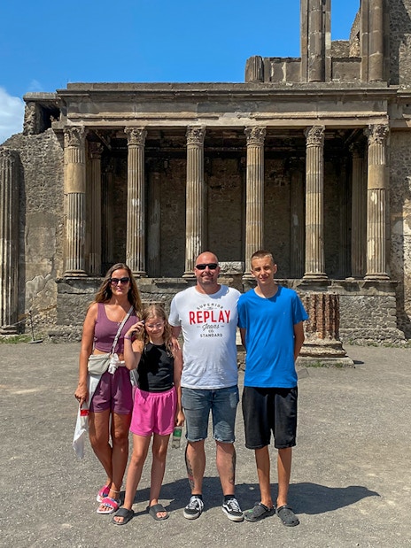 Family standing in front of ancient ruins in Pompeii, Italy.