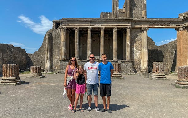 Family standing in front of ancient ruins in Pompeii, Italy.