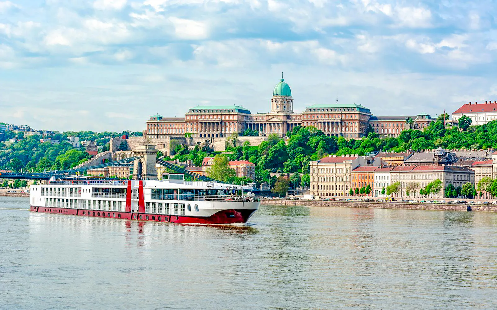 Cruise ship on the Danube River with Buda Castle in Budapest.