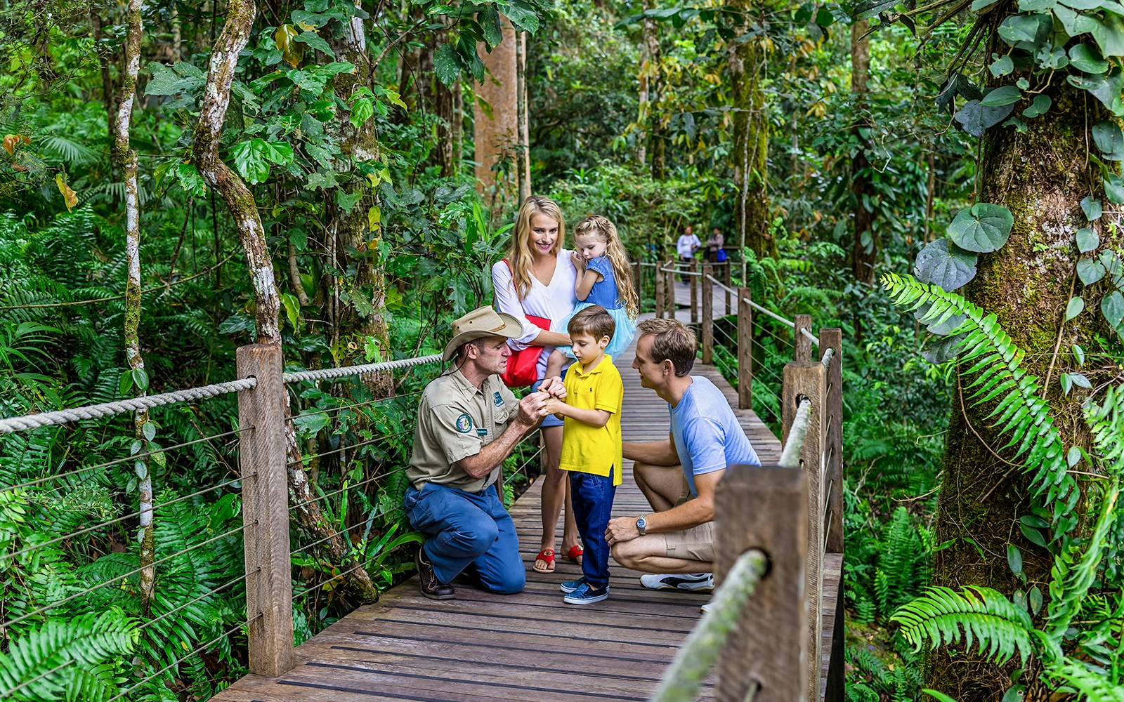 Guide explaining rainforest plants to family on Kuranda tour, Cairns.