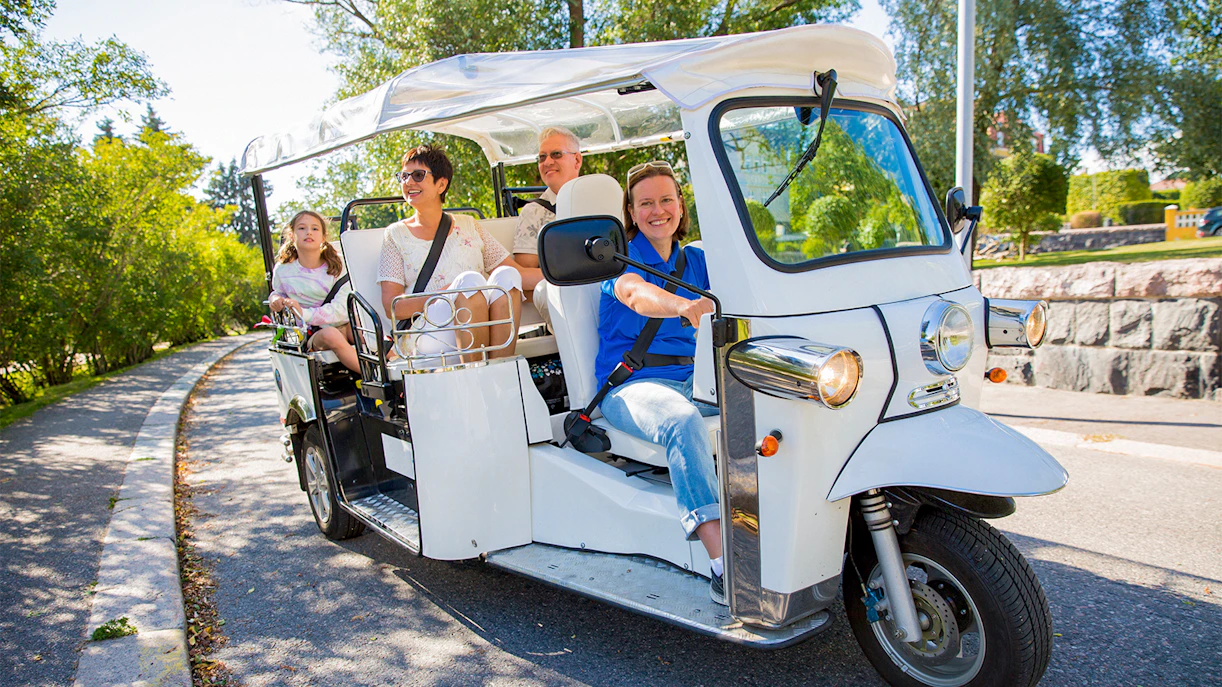 Tourists riding an electric tuk-tuk through the city center, enjoying an eco-friendly tour.