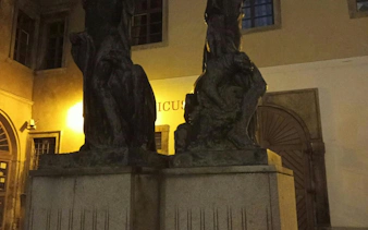 Statues in a dimly lit courtyard, part of Prague Alchemy Mission game.