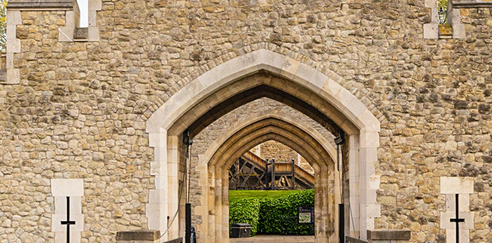 Tower of London stone entrance with arched gateway and towers.