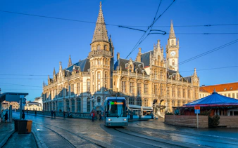 Former post office building with clock tower and tram on Korenmarkt, Ghent, Belgium.