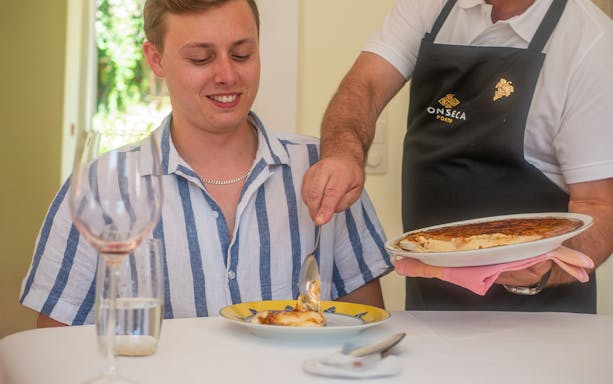 Tourist enjoying traditional dish during Douro Valley tour lunch in Porto.