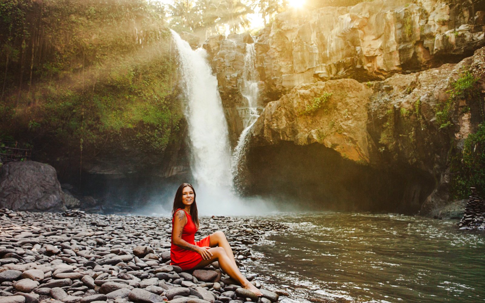 Tourist sitting by Tegenungan Waterfall in Bali, Indonesia.