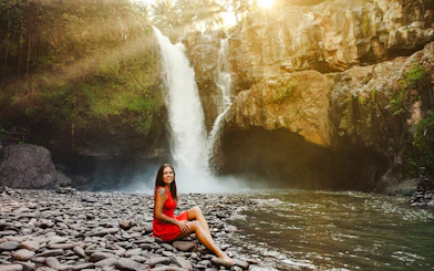 Tourist sitting by Tegenungan Waterfall in Bali, Indonesia.