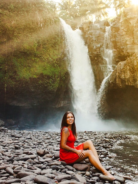 Tourist sitting by Tegenungan Waterfall in Bali, Indonesia.