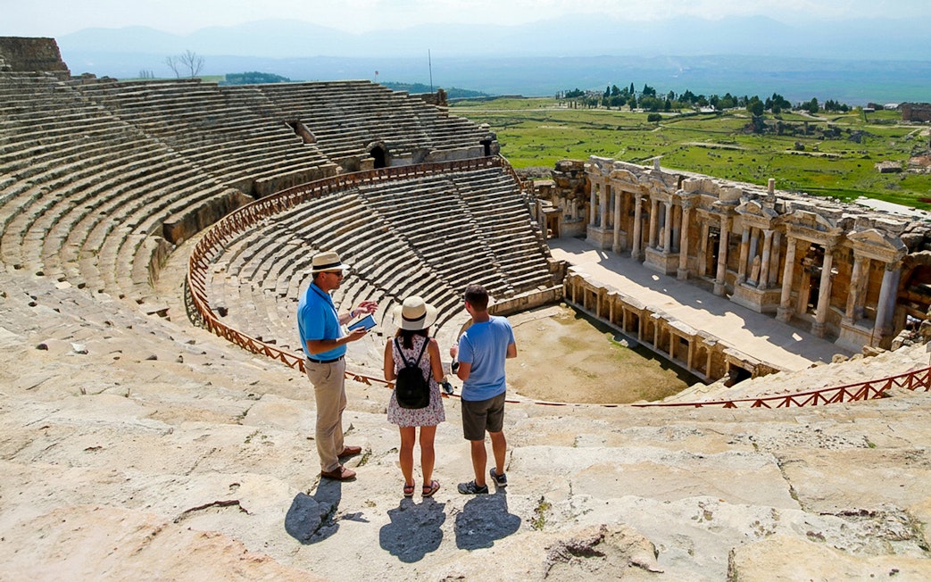 Guide explaining to tourists at the ancient theater near Apollo Temple, Turkey.