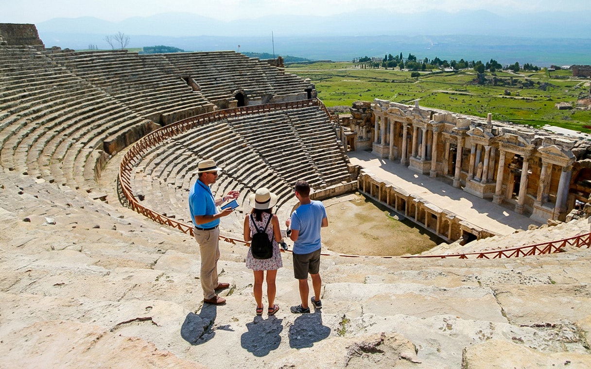 Guide explaining to tourists at the ancient theater near Apollo Temple, Turkey.