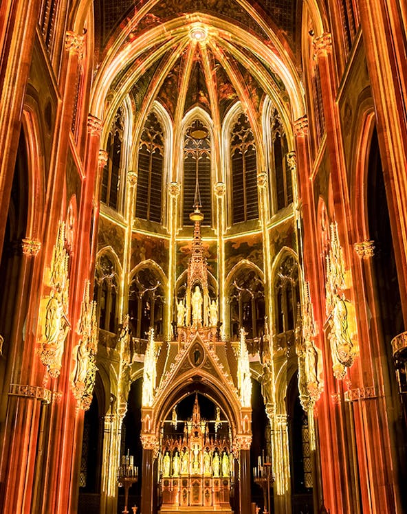 Gothic cathedral interior with illuminated arches and altar, Sainte-Chapelle, Paris.