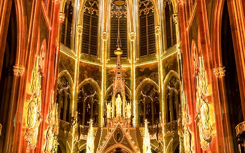 Gothic cathedral interior with illuminated arches and altar, Sainte-Chapelle, Paris.
