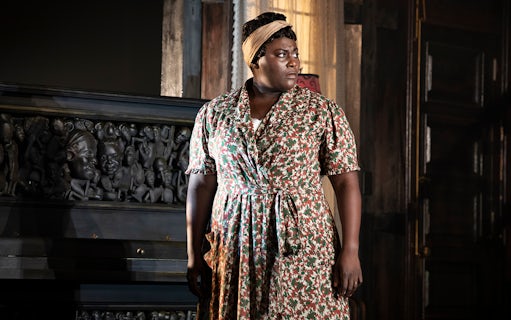 Woman standing beside a carved piano in a scene from "The Piano Lesson.
