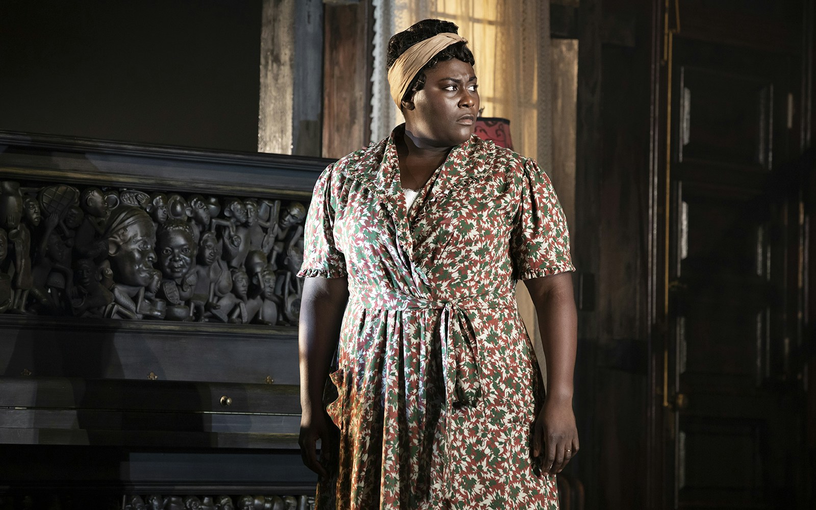 Woman standing beside a carved piano in a scene from "The Piano Lesson.