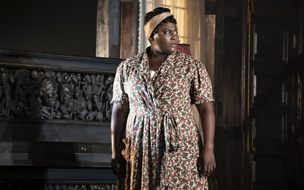 Woman standing beside a carved piano in a scene from "The Piano Lesson.