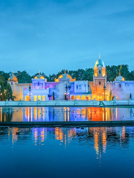 Efteling theme park illuminated at night, reflecting on water in Amsterdam.