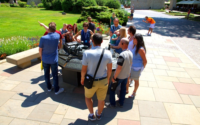 Group of tourists on a guided tour at Wawel Castle, viewing a model of the castle grounds.