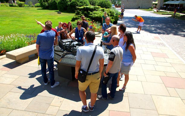 Group of tourists on a guided tour at Wawel Castle, viewing a model of the castle grounds.
