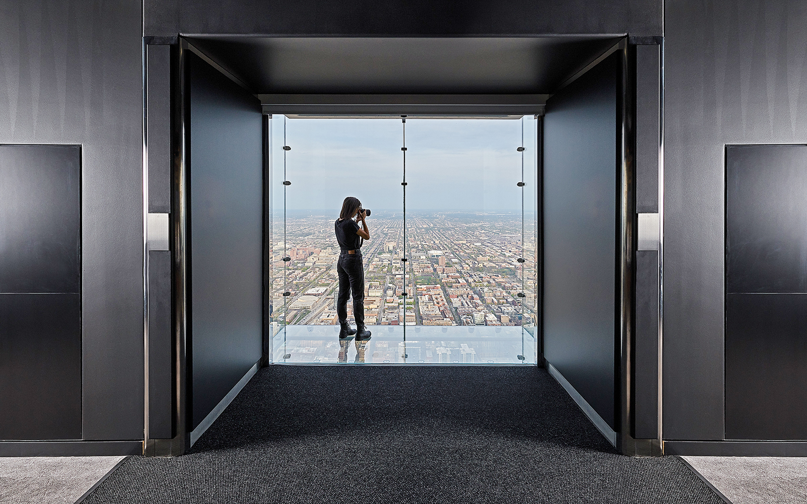 Person photographing cityscape from Skydeck Chicago at Willis Tower.