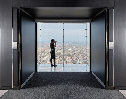 Person photographing cityscape from Skydeck Chicago at Willis Tower.