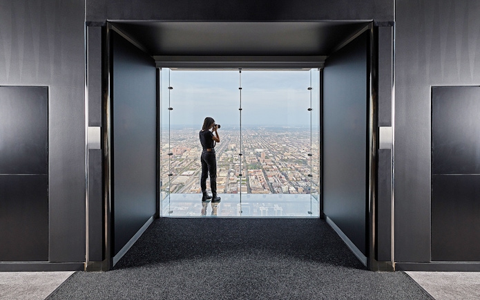 Person photographing cityscape from Skydeck Chicago at Willis Tower.