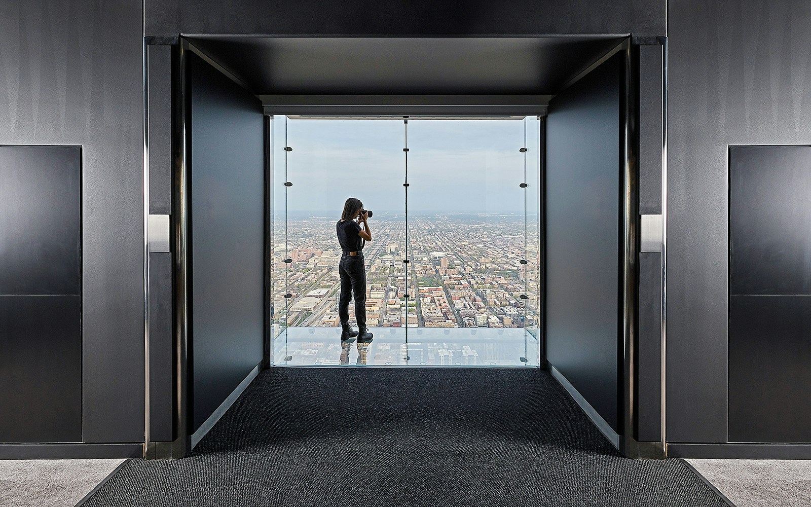 Person photographing Chicago skyline from Skydeck in Willis Tower.