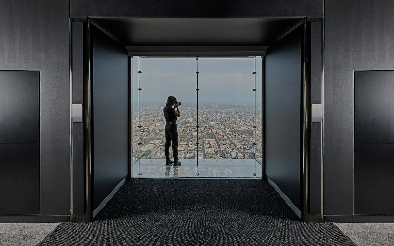 Person photographing Chicago skyline from Skydeck in Willis Tower.