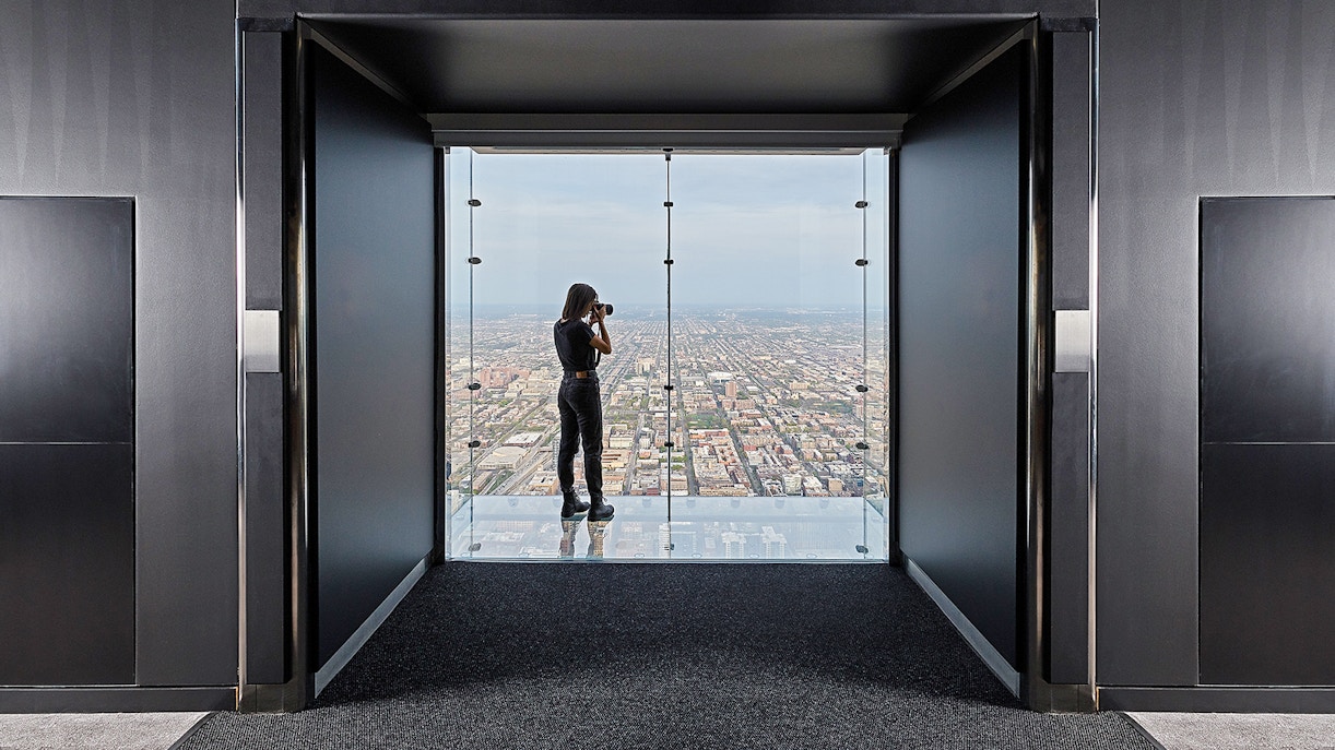 Person photographing cityscape from Skydeck Chicago at Willis Tower.