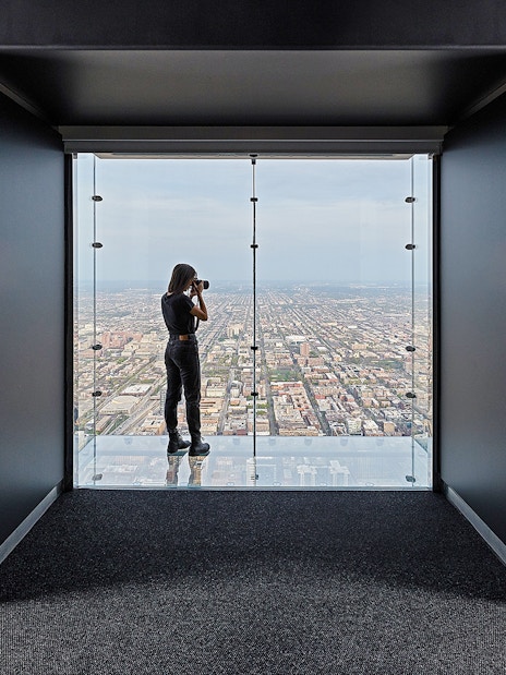 Person photographing cityscape from Skydeck Chicago at Willis Tower.