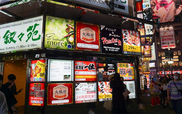 Shinjuku street with vibrant neon signs and people enjoying a night out in Tokyo.