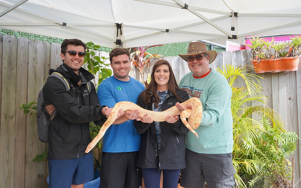 Group holding a large snake during Holiday Park animal encounter experience.