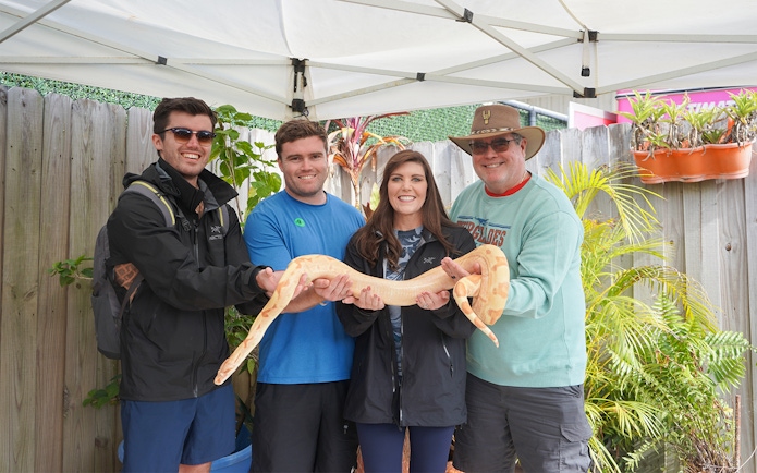 Group holding a large snake during Holiday Park animal encounter experience.